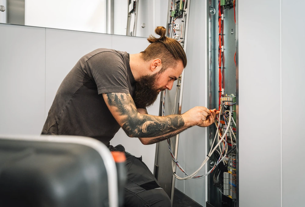 Techniker arbeitet an der Verkabelung eines geöffneten Schaltschranks