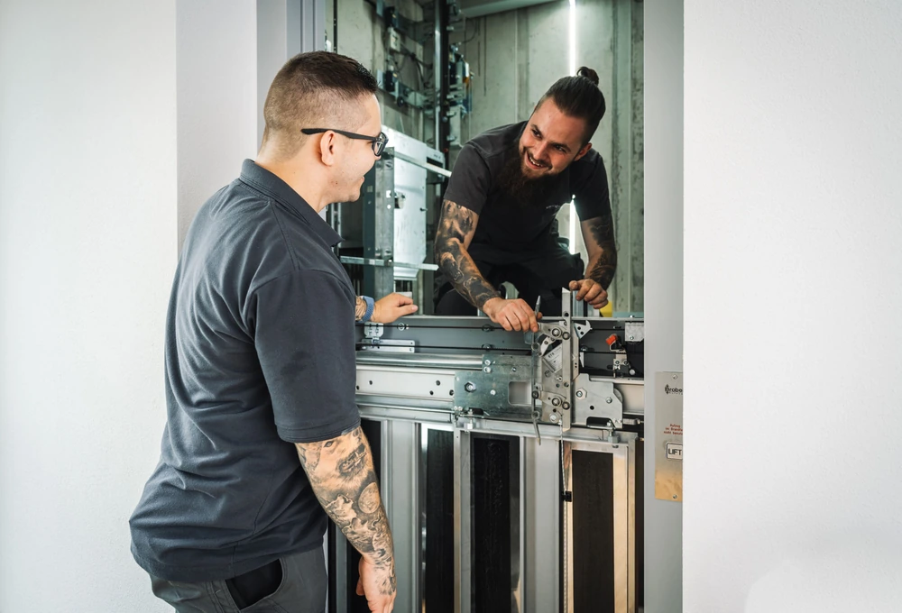 Zwei Techniker arbeiten an der Mechanik eines Aufzugs