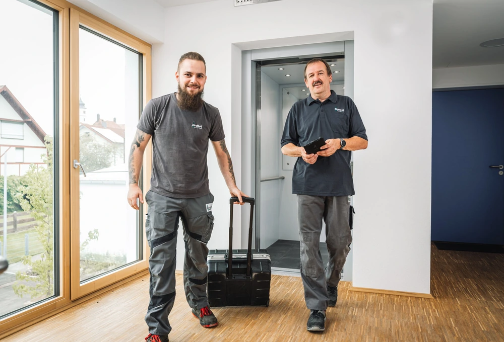 Zwei Servicetechniker mit Werkzeugkoffer in einem hellen Eingangsbereich