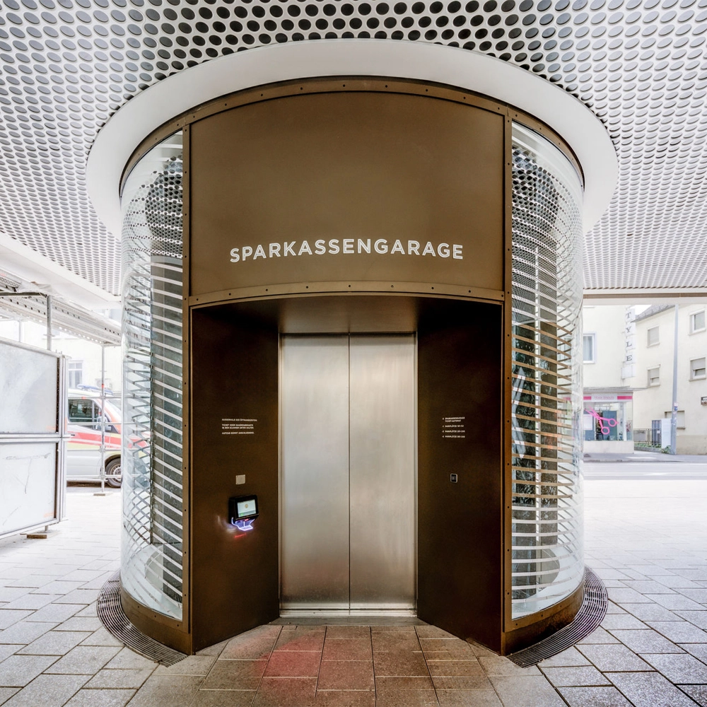 Eingang der Sparkassengarage mit gläsernem Aufzug und Zugangsterminal