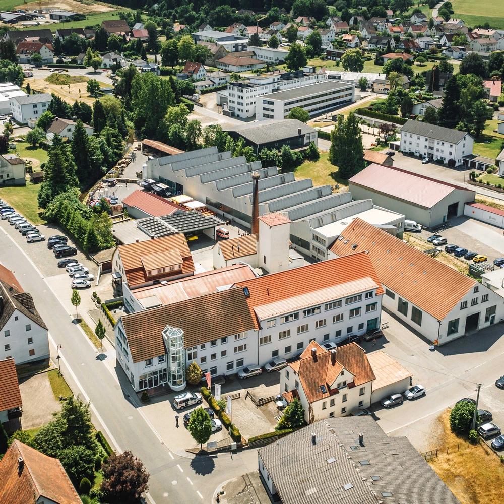Luftaufnahme eines Ortes mit Wohnhäusern, Gewerbebetrieben, Straßen und umliegenden Feldern