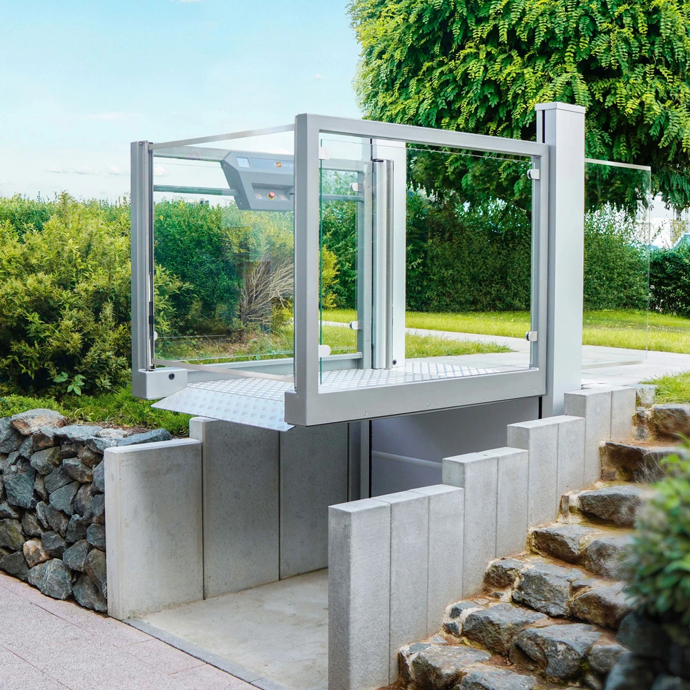 Gläserner Außenaufzug mit Plattform für barrierefreien Zugang zwischen zwei Ebenen