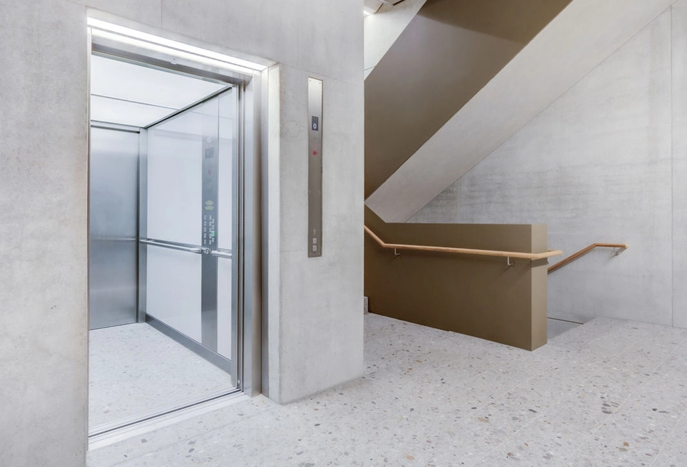 Offener Aufzug neben einer Treppe in einem modernen Gebäude