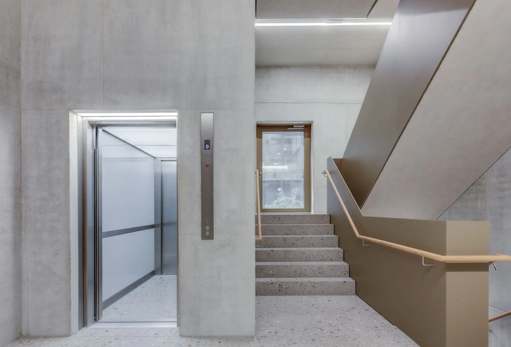 Geöffneter Aufzug neben einer Betontreppe in einem modernen Gebäude