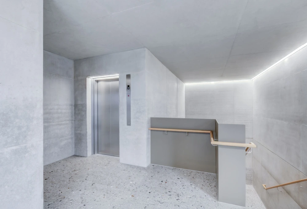 Heller Flurbereich mit Aufzug und Treppe mit durchgehenden Handläufen