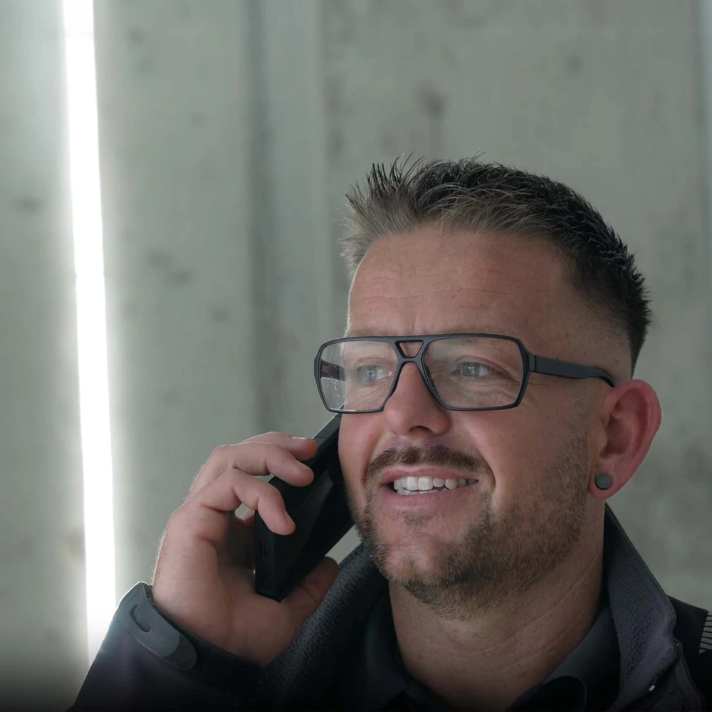 Mann mit Brille telefoniert mit einem Mobiltelefon