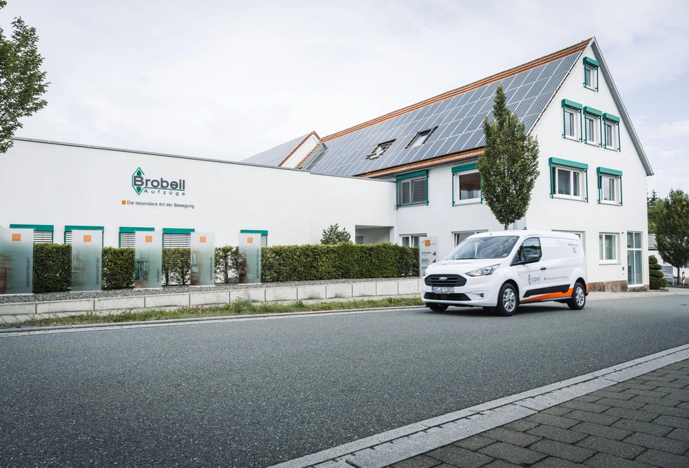 Firmengebäude von Brobeil Aufzüge mit Solaranlage und weißem Firmenfahrzeug auf der Straße