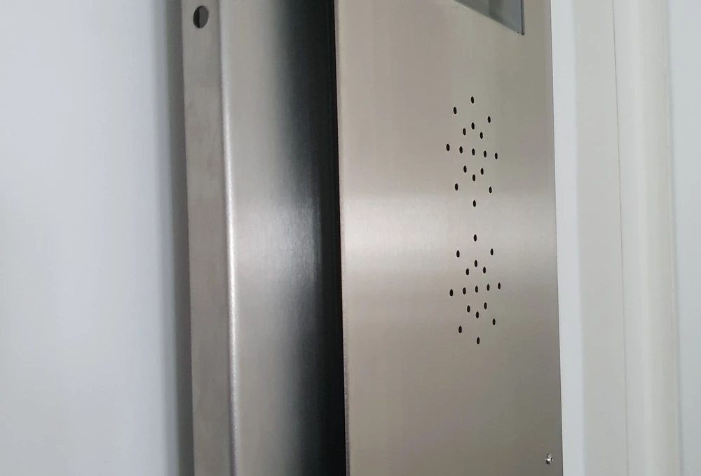 Metallene Gegensprechanlage mit Lautsprecheröffnungen neben einer Tür