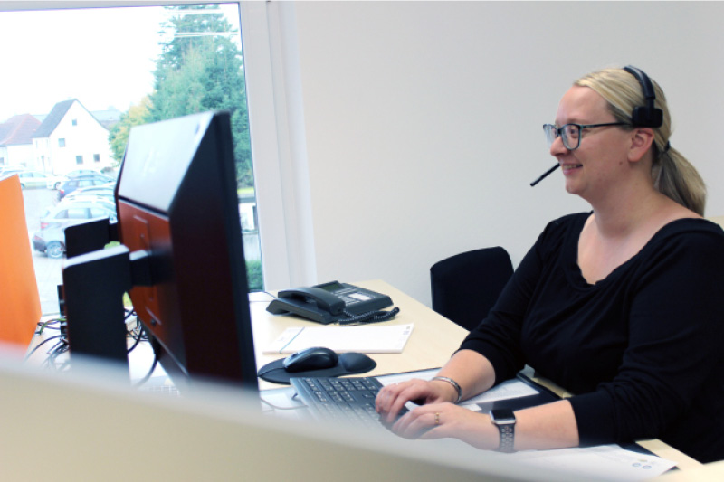 Frau mit Headset arbeitet an einem Computerarbeitsplatz