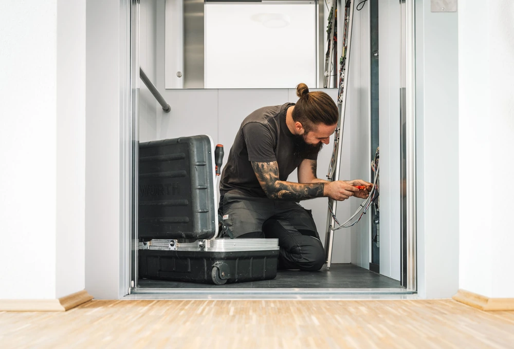 Elektriker arbeitet in einem Aufzugsschacht an der Verkabelung